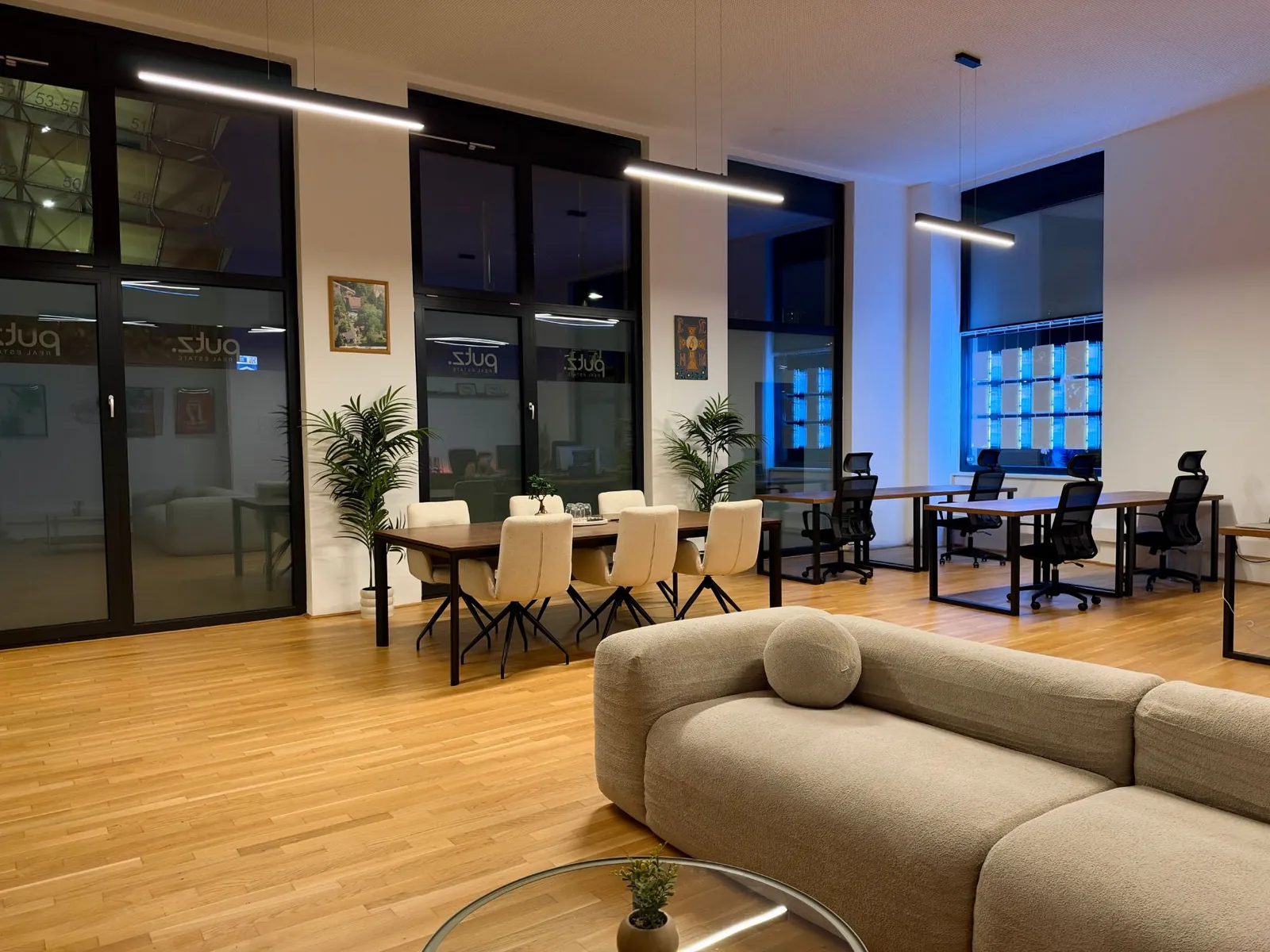 Unser Büro: Besprechungstisch, Arbeitsplätze und Lounge-Ecke mit PUTZ-Logo an der Glaswand